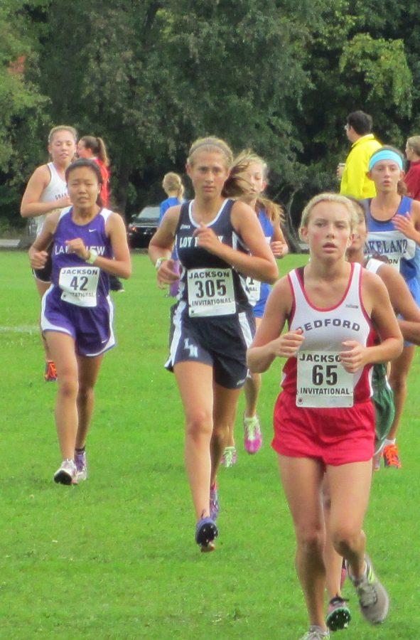 Sophomore Olivia Vande Pol, (center) running in a cross country meet for Loy Norrix Highschool. She is hoping to beat her personal best mile time of 6:30.