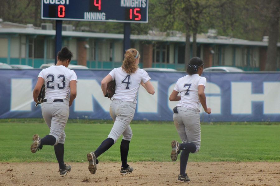 The three Loy Norrix outfielders run out to their positions in a game last spring. Many college coaches have had an eye on the three lady Knights. From Left to Right: #23 Keisha Harris, #4 Megan Lohner, #7 Maia Greer. Photo Credit / Kristi Johnson