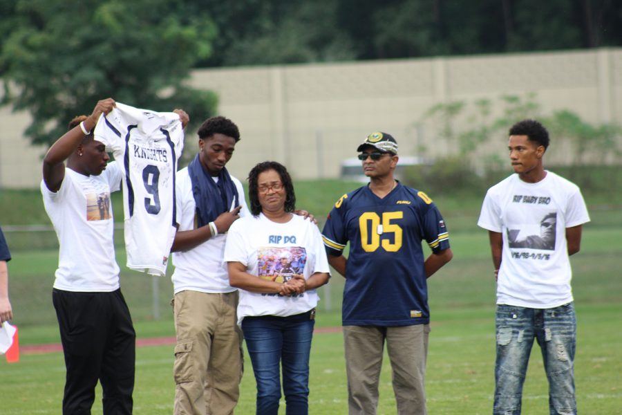 Friend, Damarquay Norman, presents to DQ’s mother, Mabel Evans, the jersey once worn by Hunter. DQ’s teammates signed the jersey for their friend, a four year football player. Photo Credit / Zachary Liddle