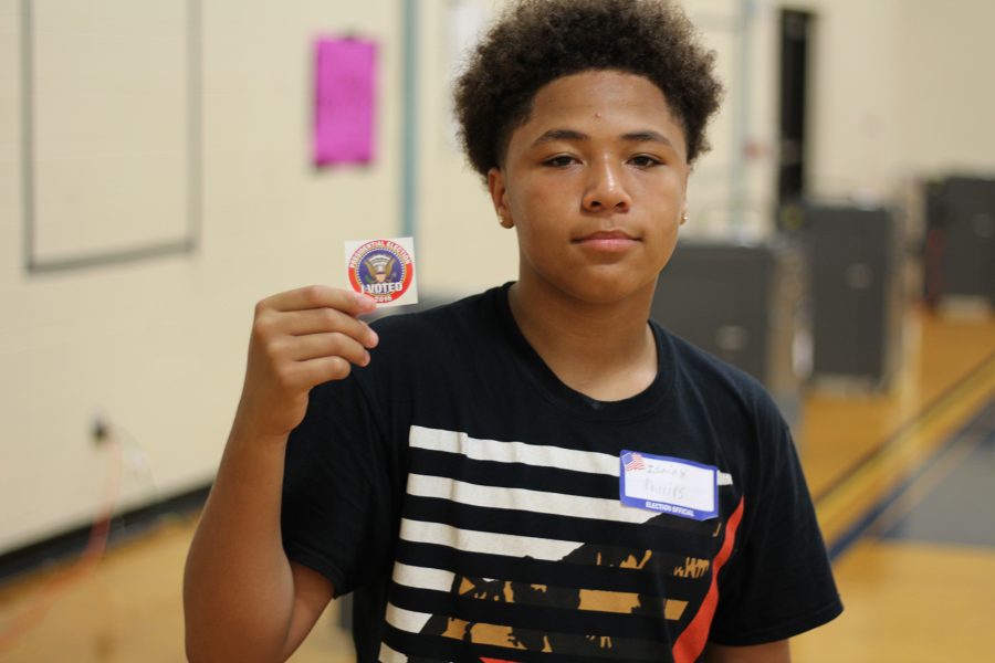 Sophomore Isaiah Phillips poses with an I Voted sticker. Phillips volunteered to help run the mock election. Photo Credit / Sidney Richardson