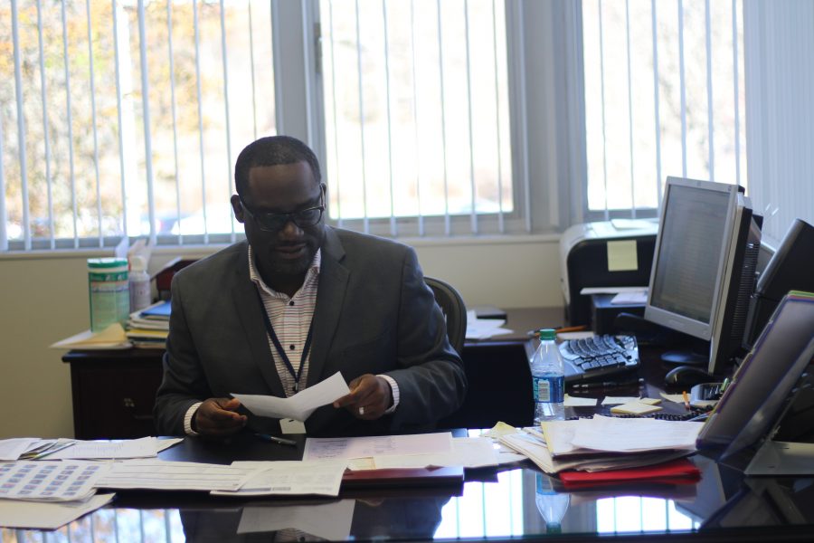 Johnny Edwards looks over new work that’s been piling up since his arrival. On top of the new work as principal, he also has to tackle being the Director of Secondary Education. Photo Credit  / Brandon Schnurr