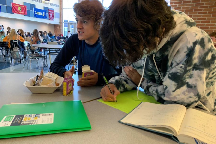Senior Nolan Tribu (left) and senior Adam Ismaili-Alaoui (right) socialize on their lunch break in school. Ismaili works hard on an assignment while Tribu enjoys his lunch and chats.
