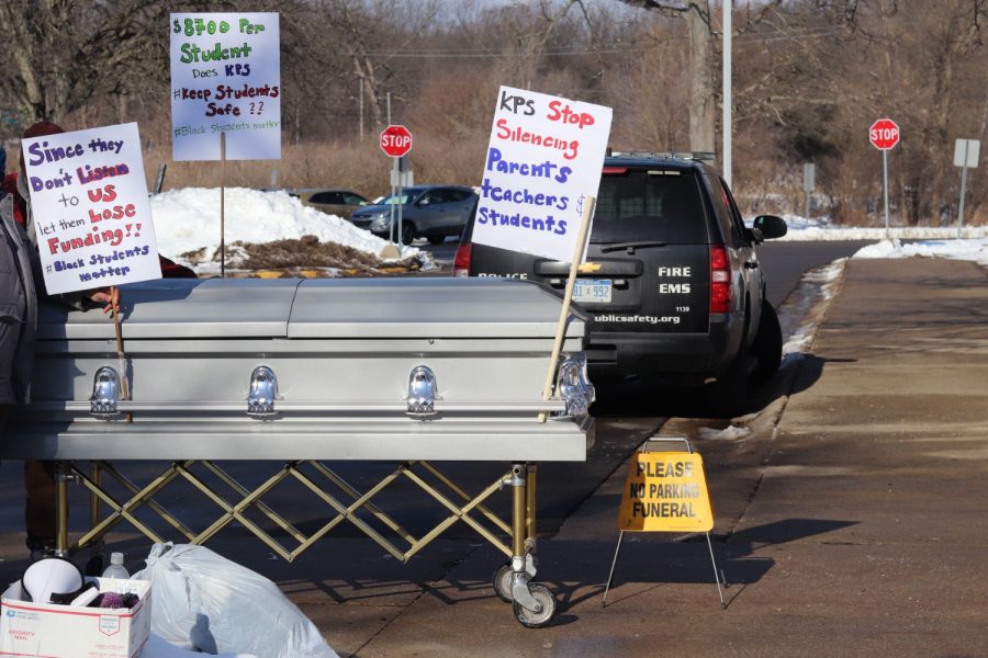 Protesters prop signs up against a large, silver casket. Shortly after, the demonstrators were asked to remove the display. 