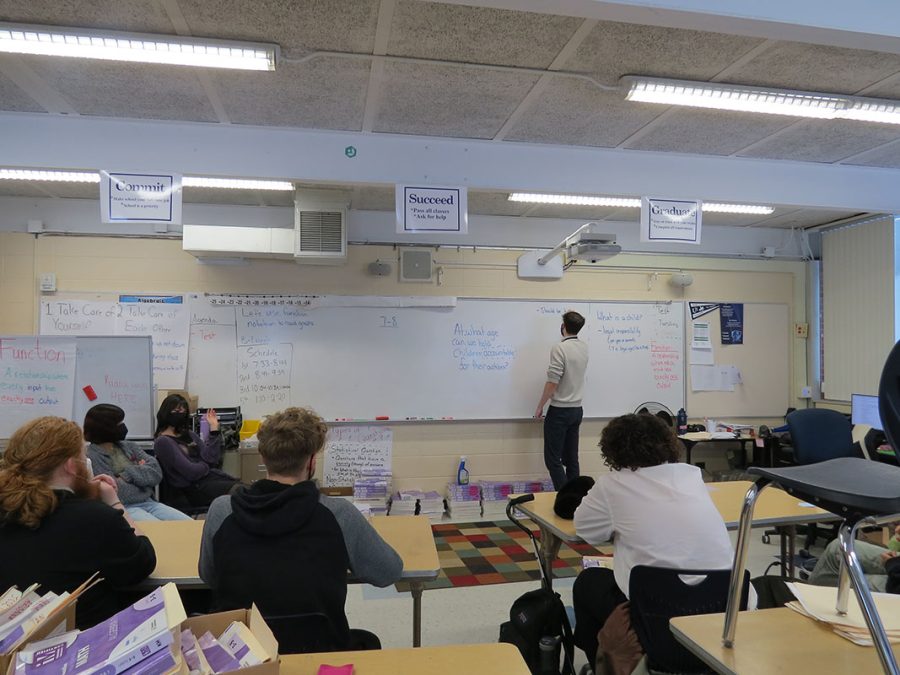 Joseph Zarn writing philosophical questions on the board. He and the club discuss ideas related to society, individuals, and interesting concepts during their time together.
