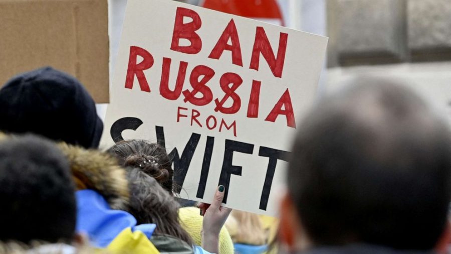 Protest signs urges a ban of Russia from the SWIFT financial system, an action that has since been taken by the United States and various other NATO countries. 