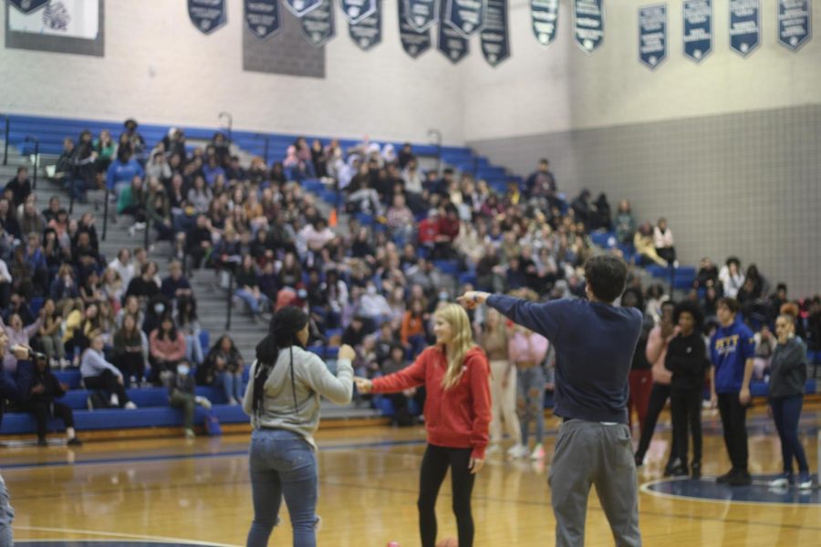 Senior James Rocco, conducts a deciding game of Rock, Paper, Scissors between junior Nia Moncrief and sophomore Anna Miedema. Students watch the game from the bleachers.