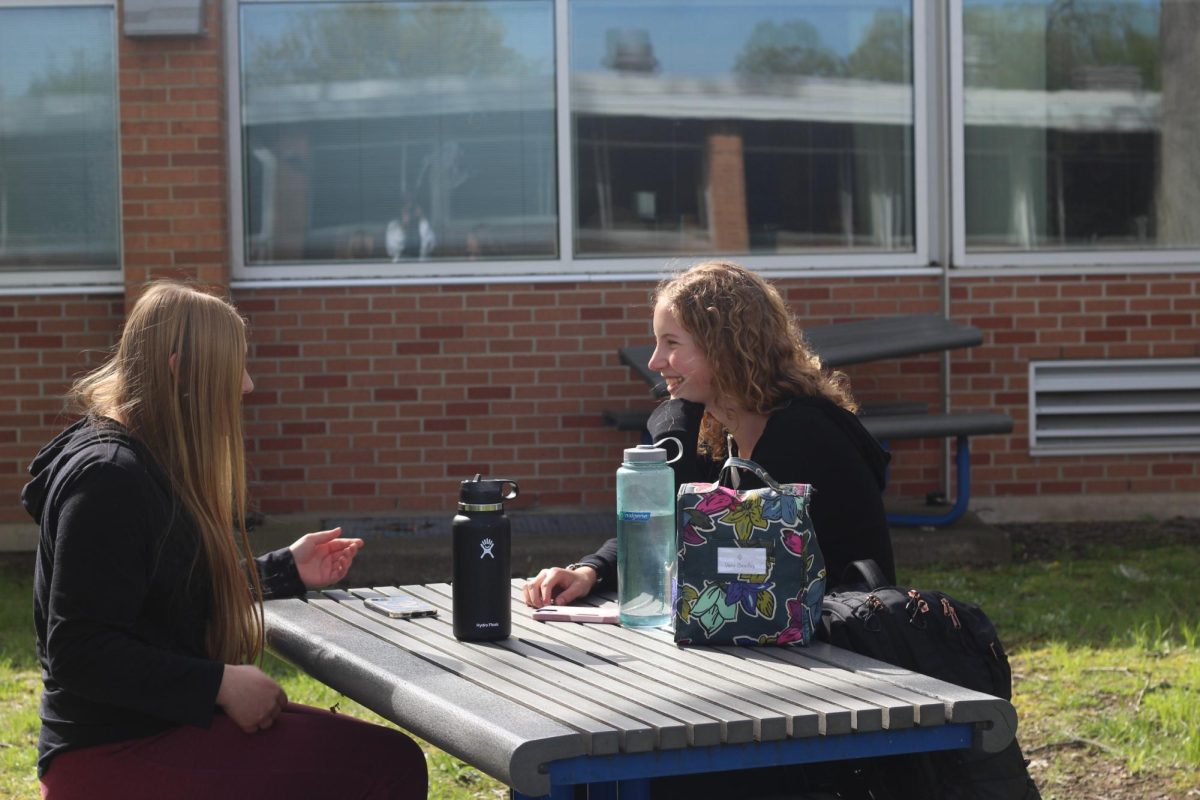 Senior Grace Guthrie and junior Macy Daniels enjoy the sun during lunch time at Loy Norrix. They are in good moods as it is sunny and warm out, but not too hot. 