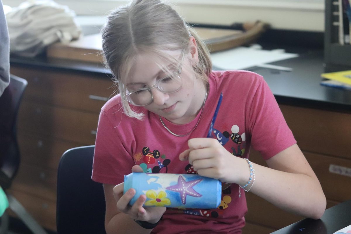 Freshman Carter Moon works hard on her painted-can art project. Moon enjoys art with her friends, as it is a fun class and she can get her work done.