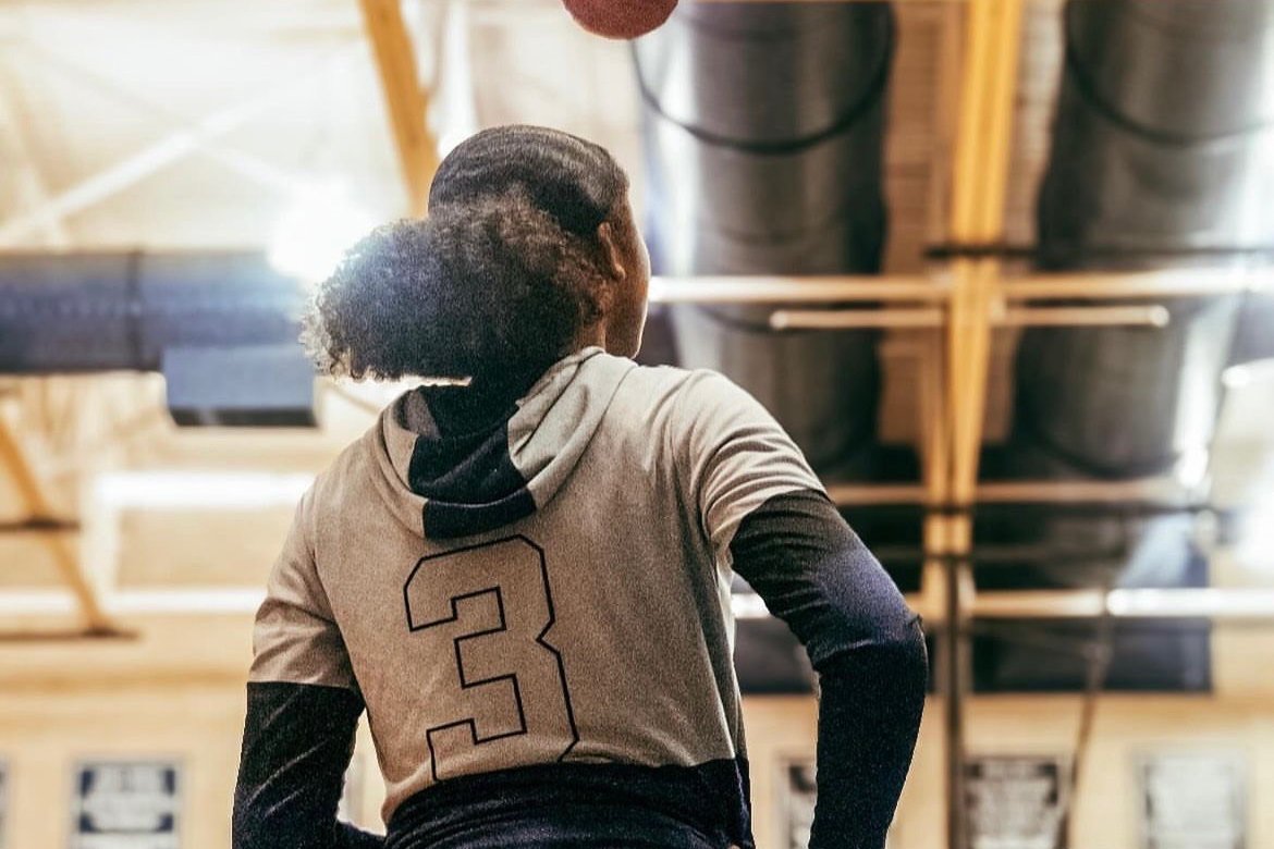 Jordyn Ivy stands and watches her teammates while warming up for a game. Ivy is a varsity basketball player. 
