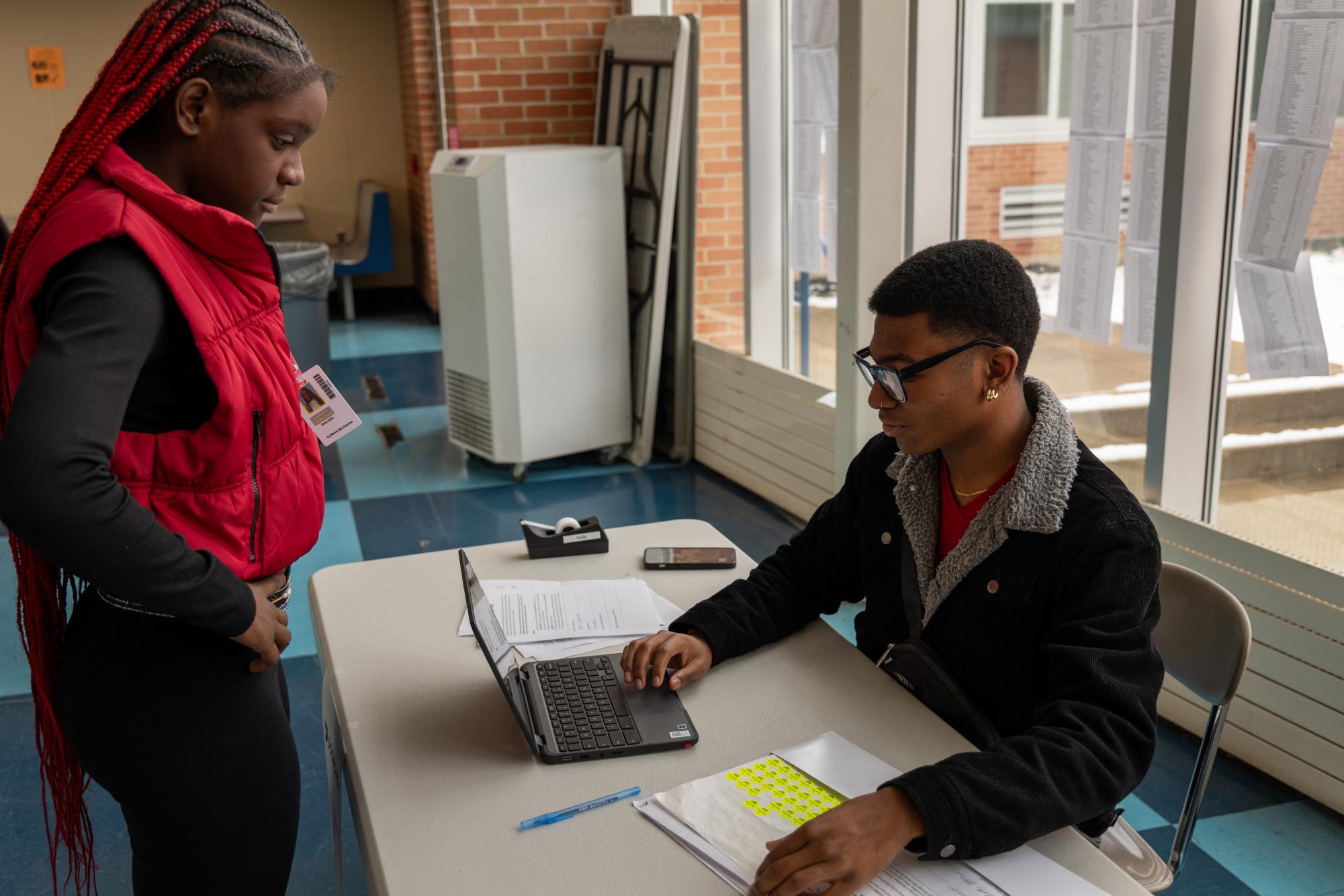 Junior Paul Evans helps Kymora Buchanan get a dash-pass during lunch. The dash-pass allows students to order food through delivery apps to the schools during lunch time. 
