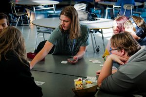 Freshman August Pitts deals a hand of cards to sophomores Mia Gates, Jackson Gates and Kaii King during a game of Blackjack. People often play card games during lunch to pass the time. 