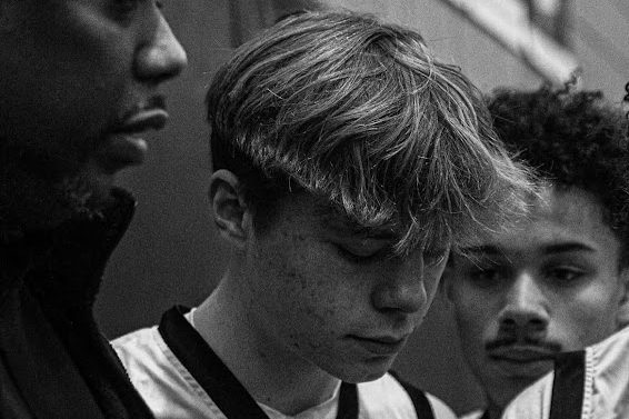 Freshman Graham Sleper listens to his coach, Richard Rashad, in the pre-game team huddle. Sleper hopes to continue playing basketball throughout high school.