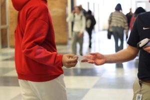 Andrew Muysenberg, Freshman Academy Principal, hands a student a  tardy pass. If a student gets 6 tardies in a week, they get suspended. 