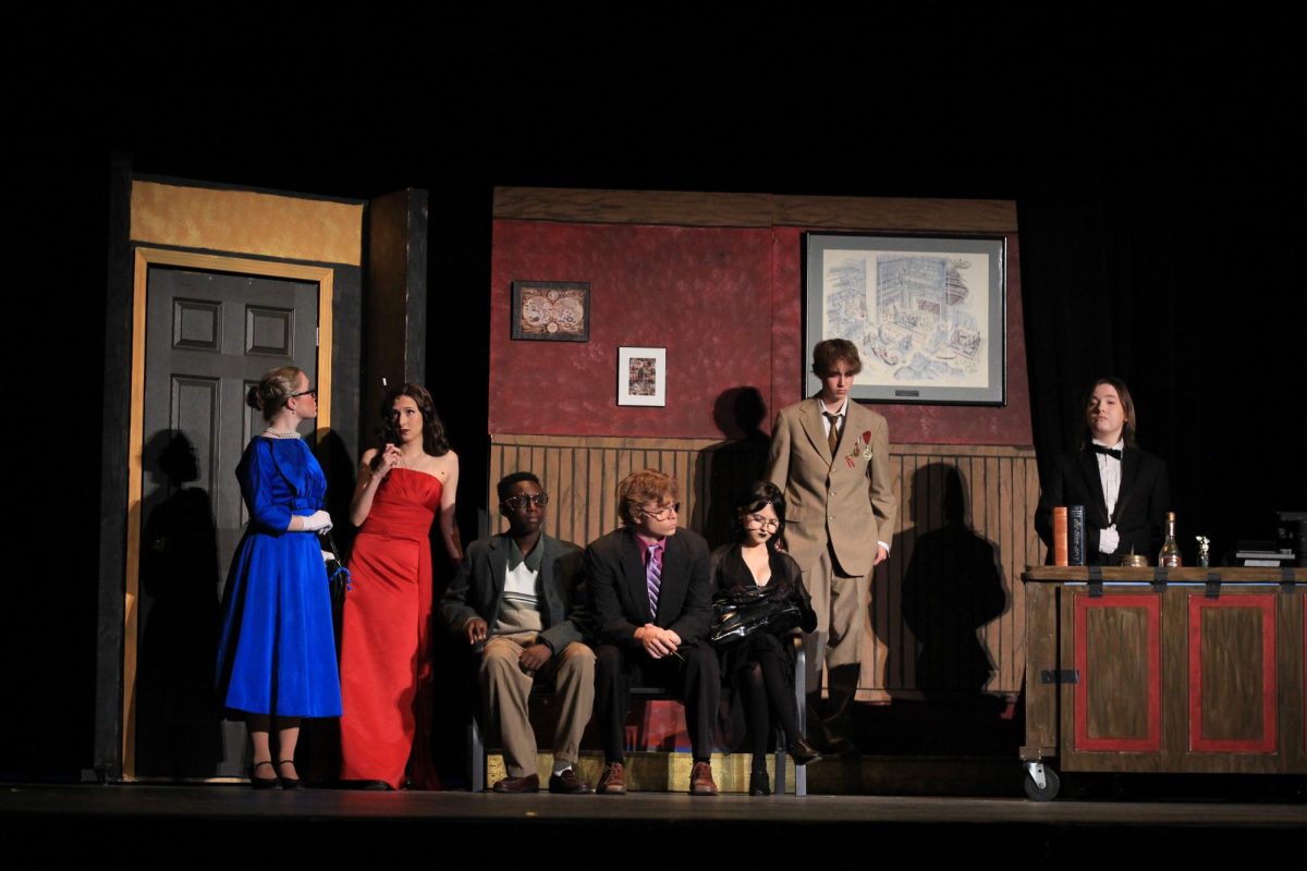 The cast of Clue anticipate Mr. Boddy's arrival while Wadsworth is revealing their blackmail. 