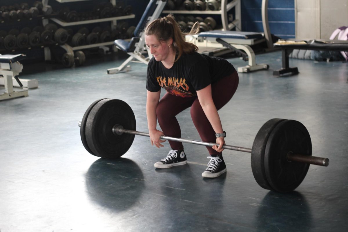 Club advisor and paraprofessional Abigail Dantes demonstrates a deadlift to club members. 
